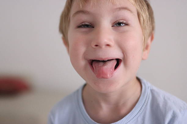 istock Young boy sticking out tongue making playful face 2250930462