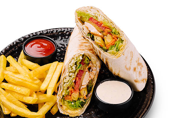 Delicious wrap with fries served on a black plate in a casual setting