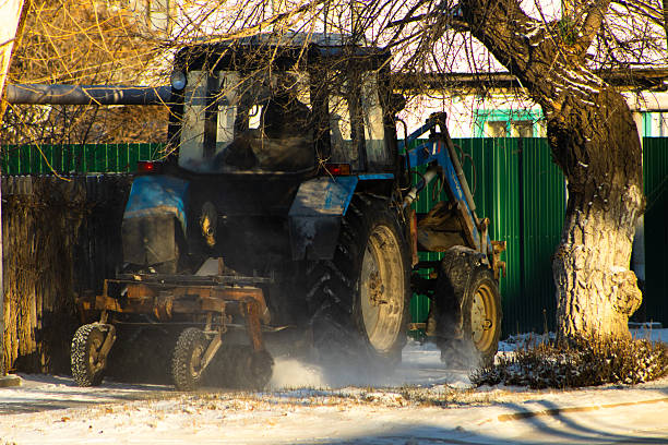 A shot capturing the rear and right side of a large, heavy-duty utility tractor, painted an aged industrial blue, actively engaged in snow removal
