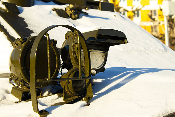 shot focused on a single, round headlight of a large, dark olive-green military or heavy-duty vehicle