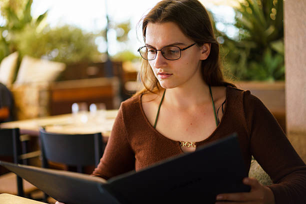 istock Woman reading menu, deciding what to order in restaurant. 2250939504