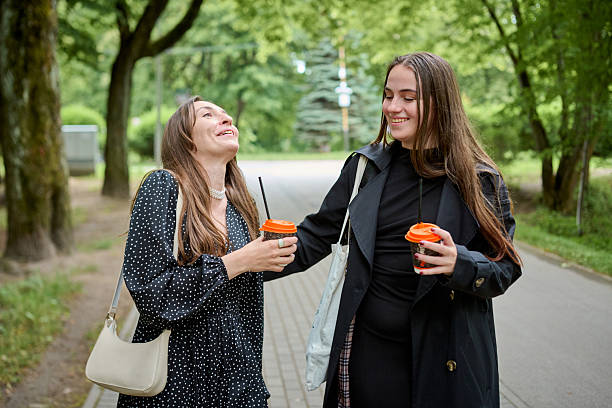 istock Young girlfriends gossiping and drinking coffee outdoors in park 2250942505