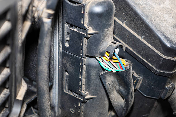 ​A close-up shows an opened wire harness with multicolored cables emerging from a fuse box or another electrical component in the engine bay.