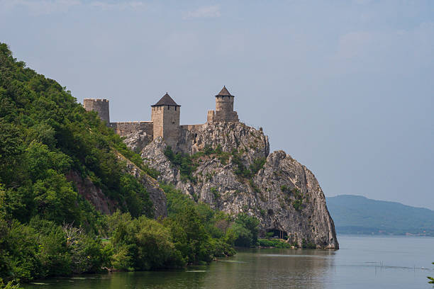 Scenic view of the medieval Golubac Fortress rising on a rocky cliff above the Danube River in Serbia. Ancient walls, towers and dramatic landscape attract tourists and history lovers.