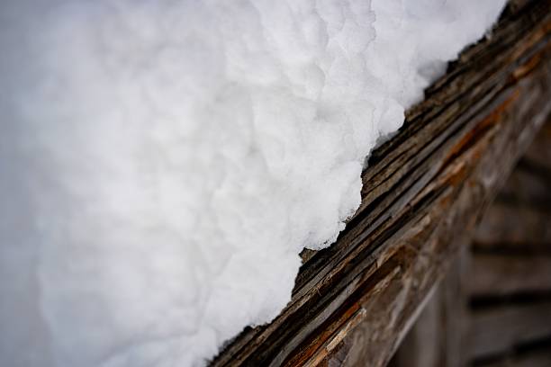 Close-up texture shot of old, rustic wooden shingles covered in fresh white snow.