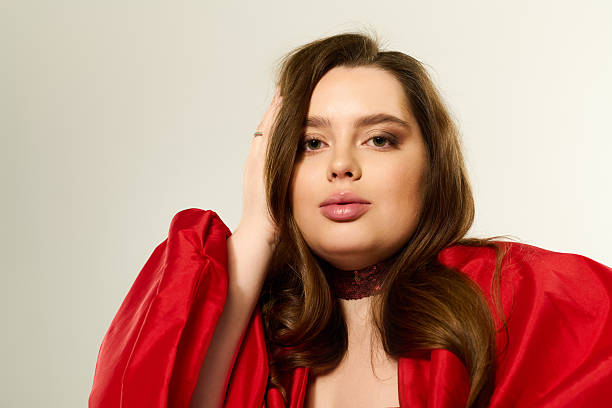 A plus-size young woman joyfully shows off her red holiday outfit, embracing the season.