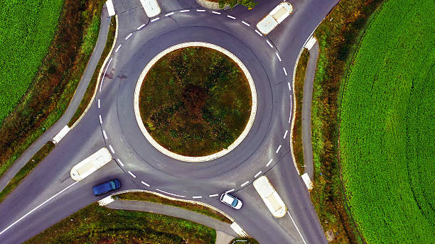 istock Roundabout traffic circle aerial view with cars circulating, green fields surrounding complex road infrastructure 2250950674