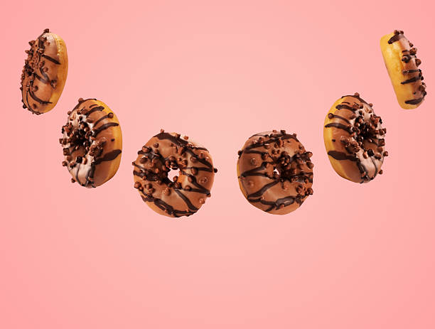istock Donuts in mid-air with chocolate and sprinkles on a pink background 2250953113