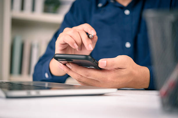 istock businessman holding a smartphone and a pen while working with a laptop at a desk, checking financial stocks, mobile banking, and trading online. Concept of technology and digital communication. 2250953388