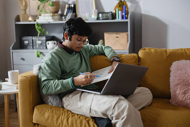 istock Indian Male Student Studying Remotely from Home Using Laptop on Sofa 2250953643