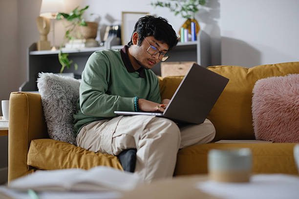 istock Indian Male Student Studying Remotely from Home Using Laptop on Sofa 2250953658