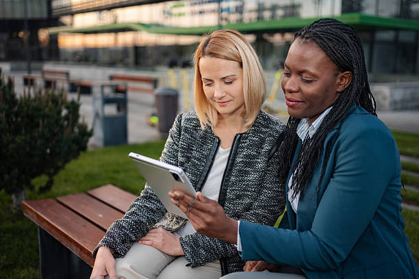 istock Diverse businesswomen discussing work using digital tablet outdoors 2250954079
