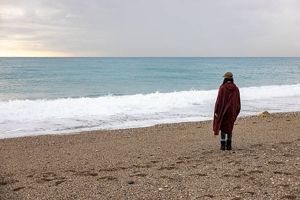 Peaceful scene of a solitary woman standing on the beach, capturing a sense of calm, freedom, and introspection by the sea