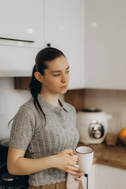 istock Thoughtful Woman Holding a Mug in a Cozy Kitchen Setting 2250961249