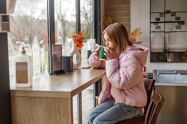 Teen girl enjoying warm drink at cafe window