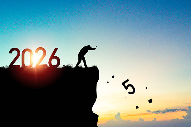 A silhouette man pushes the falling number 2025 off a cliff symbolizing moving forward into 2026 with new beginnings future goals for preparation happy new year concept.