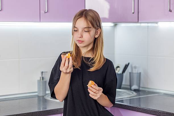 Girl holding peeled tangerine segments in kitchen