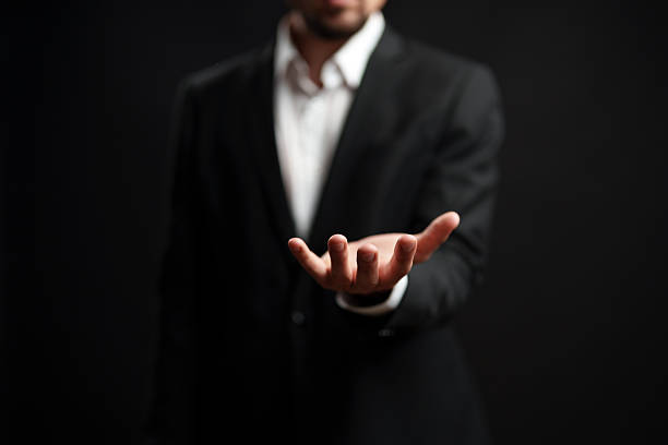istock Professional man extending his hand in a welcoming gesture against a dark background 2250964723