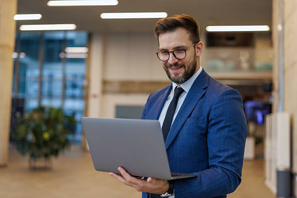 istock Businessman smiling working on laptop in modern office 2250972941