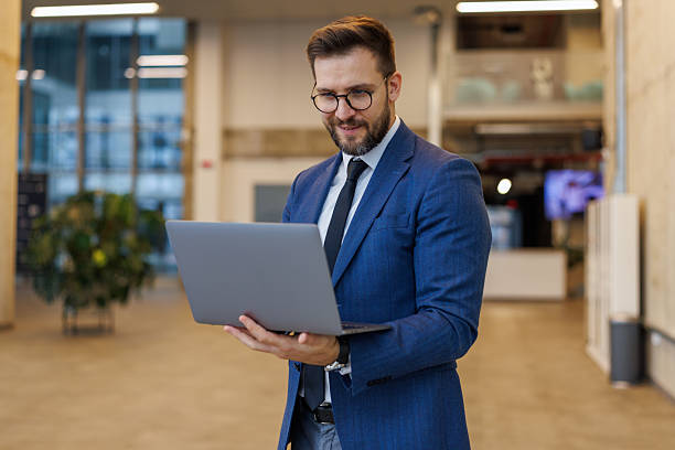 istock Businessman smiling working on laptop in modern office 2250972950