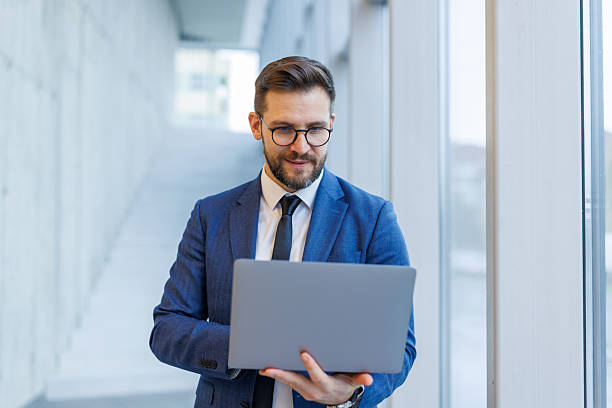 istock Businessman using laptop standing in modern office corridor 2250972956