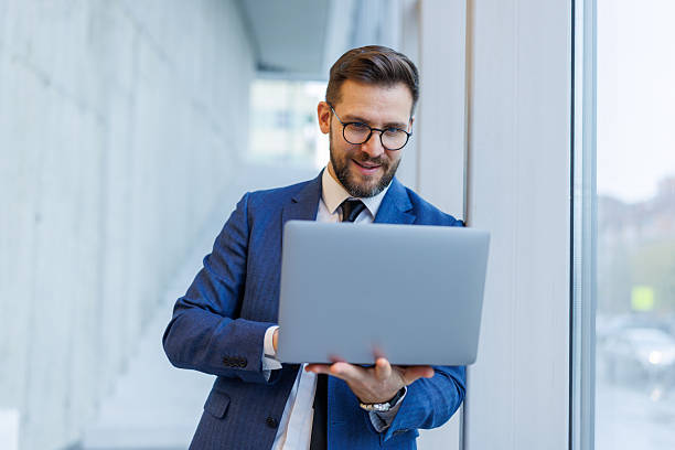 istock Businessman smiling working on laptop inside modern office building 2250972962