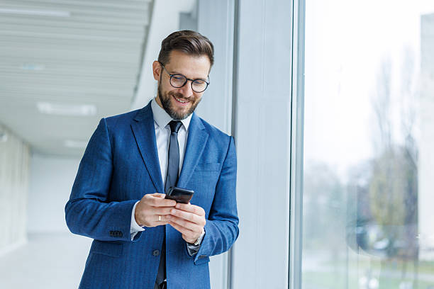 istock Businessman smiling while texting on mobile phone in office 2250973087