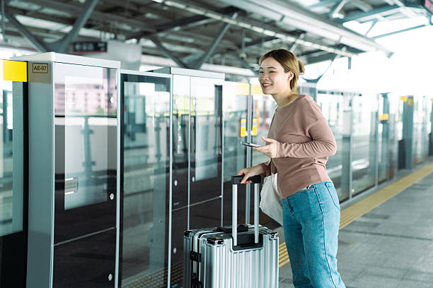 istock Asian traveler checking phone with suitcase at modern train station. 2250974048