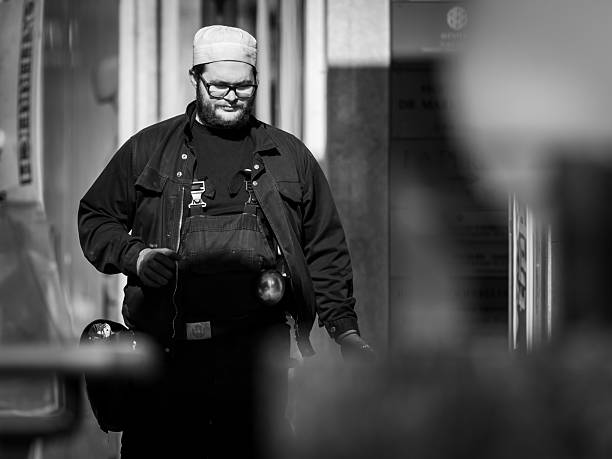 Vienna, Austria - April 7, 2020: A chimney sweeper in uniform walks along the street in springtime, captured in black and white