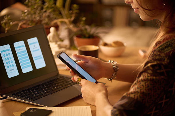 istock Young Adult Woman Using Smartphone While Working on Laptop Indoors 2250974740