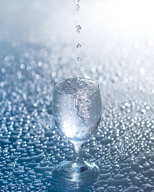 A glass of fresh water with droplets on white background