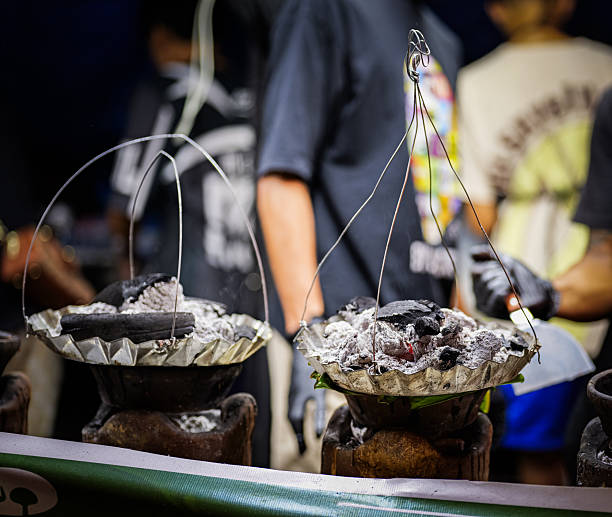 Close-up of bibingka being cooked traditionally over hot charcoal at a Filipino night market.