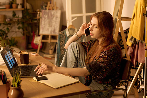istock Young Woman Working Remotely Using Laptop and Talking on Smartphone 2250981207