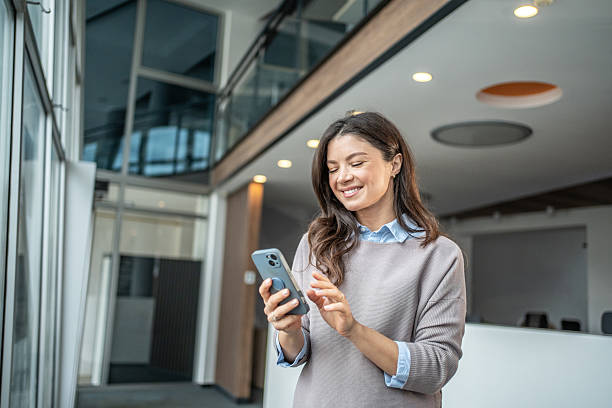 istock Businesswoman using smartphone smiling in modern office environment 2250983724