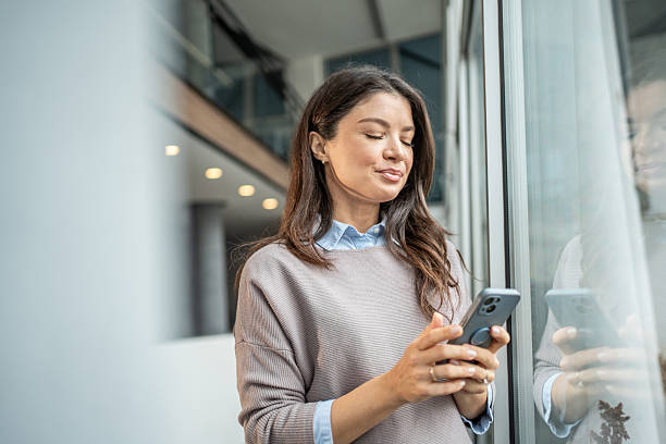 istock Woman messaging smartphone by office window with reflection 2250984494