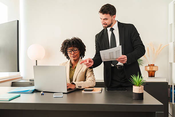 istock Business professionals collaborating at desk while discussing project details with focused expressions 2250984992