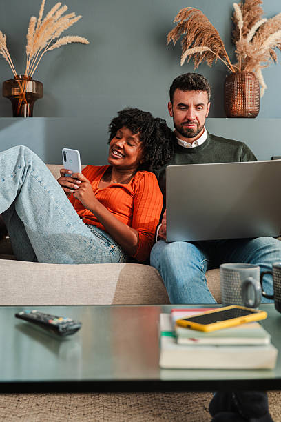 istock Couple enjoying quality time together while using smartphone and laptop in cozy living space 2250985454