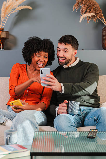 istock Happy couple sharing joyful moments while using their smartphone together on a cozy couch at home 2250988794