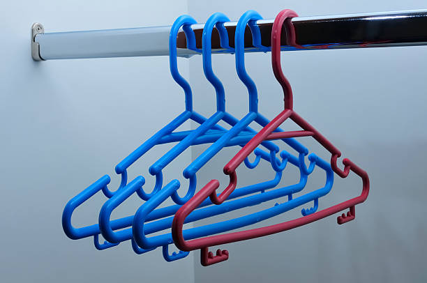 istock Three blue plastic hangers and one red hanger hanging from a sil 2250990711