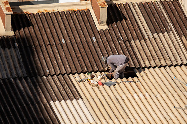 A worker stands on a roof fixing a chimney.