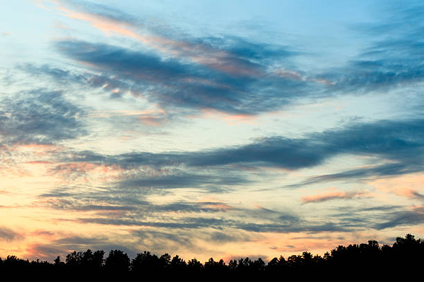 The sky is blue with a few clouds. The sun is setting and the sky is turning pink