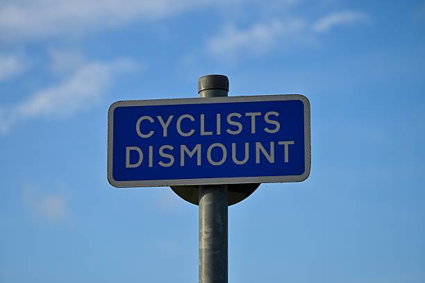 istock Cyclists Dismount Traffic Sign Against Blue Sky with Clouds 2250995121