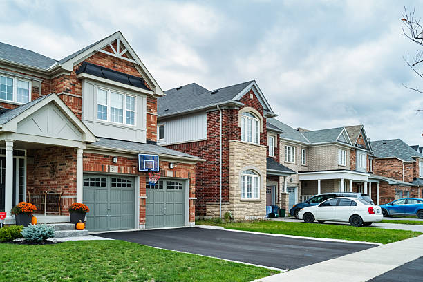 Detached brick houses in a new residential district in Bradford, Ontario, Canada, on a cloudy day.