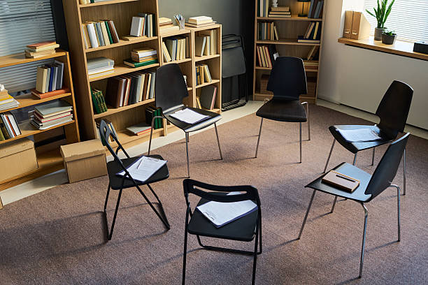 A 3D render concept of a group of chairs in a circular formation symbolizing a group therapy in session on an isolated white studio background