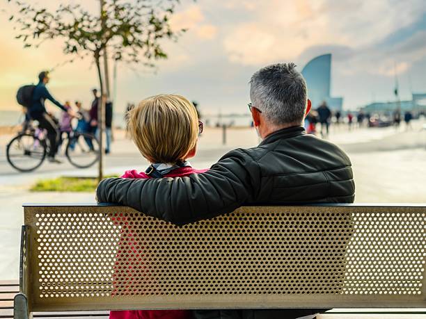 Mature couple sitting on a bench by the beach in Barcelona