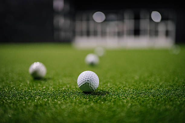 istock Indoor golf scene featuring multiple white golf balls on artificial grass, with blurred background elements creating a dynamic sports atmosphere 2251007856