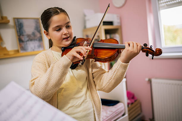 istock Young girl practices violin at home, focused on her posture and bow movement while learning a simple melody. 2251014706