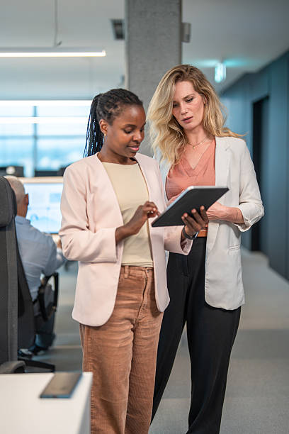 istock Engaged Mid Adult Women Discussing Project on Digital Device 2251015282