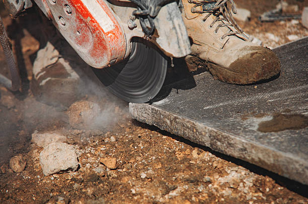 istock Builder cutting concrete paving slab with petrol concrete saw and a diamond blade during external footpath paving works close up 2251016788