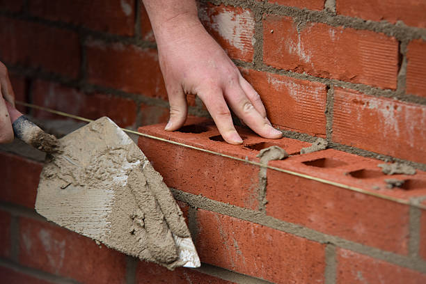 istock Close-up of Bricklayer laying red bricks on building site 2251017007